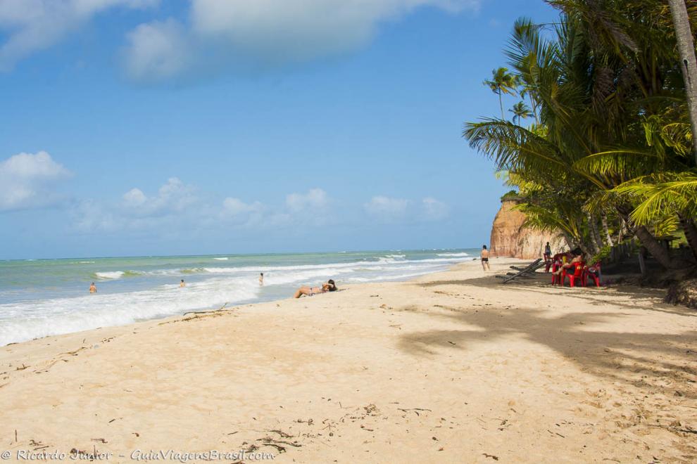 Imagem de uma pessoa tomando sol e crianças no mar na Praia Barra do Cahy em Cumuruxatiba.